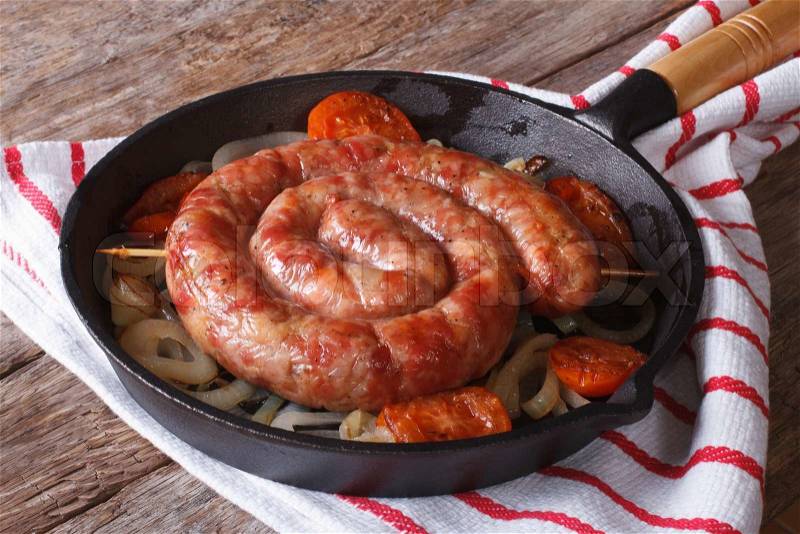 Fried sausage with onions and tomatoes in a pan closeup, rustic style , stock photo