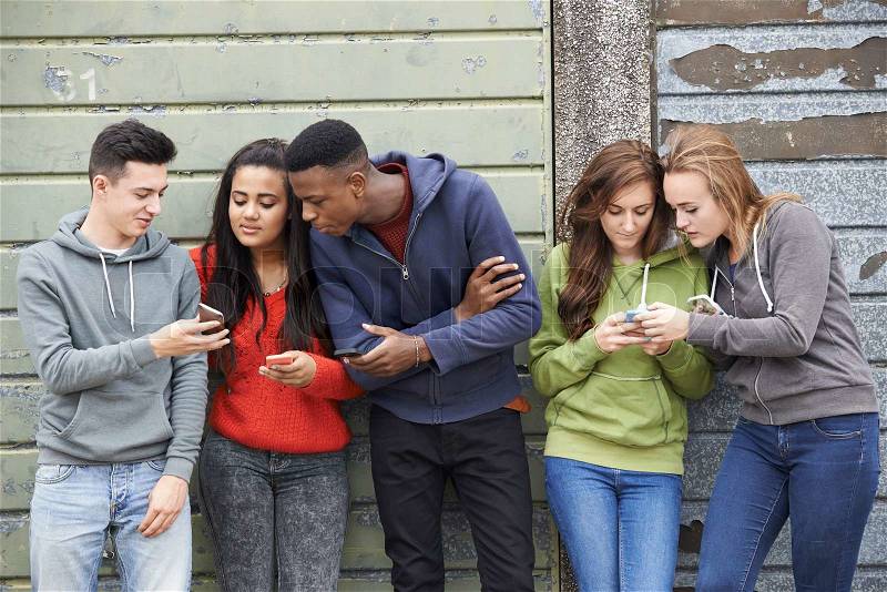 Group Of Teenagers Sharing Text Message On Mobile Phones, stock photo