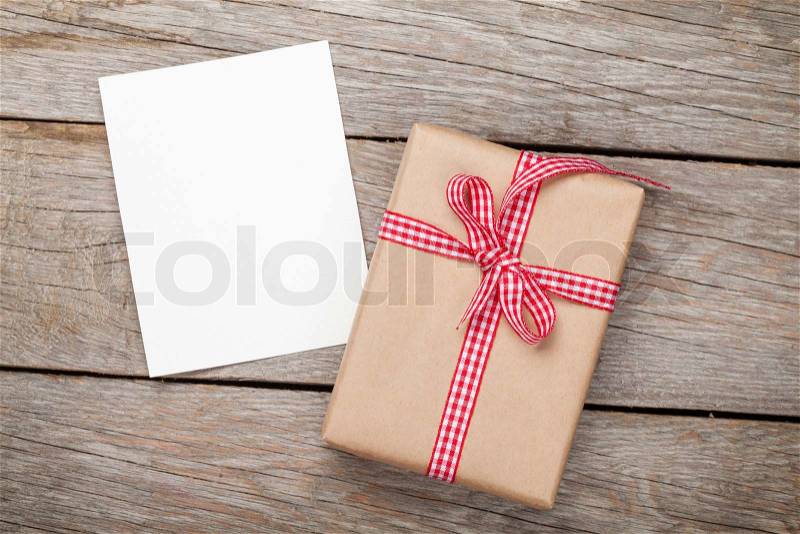 Photo frame card and gift box with ribbon over wooden table background, stock photo