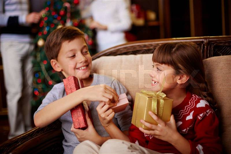 Glad boy and girl with Christmas presents in boxes, stock photo