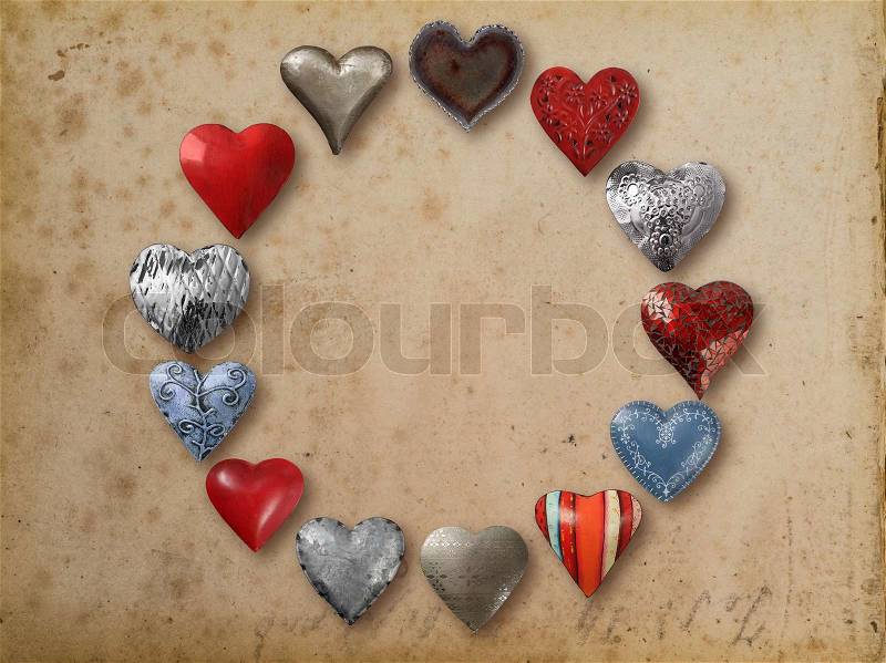 Photo of metal heart-shaped things organized in a circle over vintage paper background. , stock photo