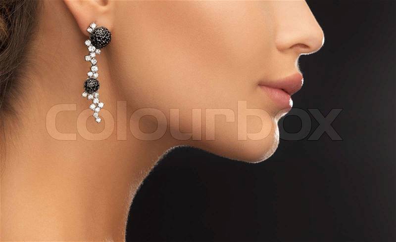 Beauty and jewelery concept - woman wearing shiny diamond earrings, stock photo