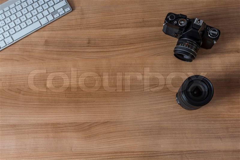 Modern keyboard and a vintage camera and a pen on a wooden desktop, stock photo