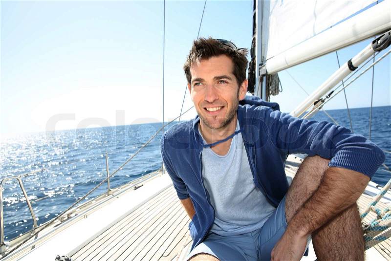 Smiling handsome man on sailboat, stock photo