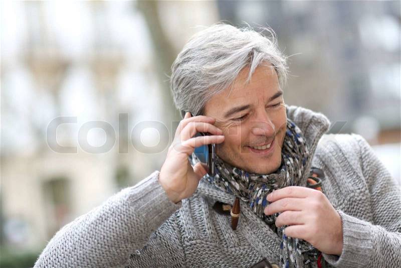 Portrait of mature man talking on phone in street, stock photo