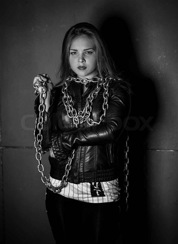 Black and white portrait of seductive woman in leather jacket with chains, stock photo