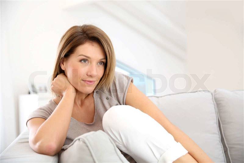 Attractive blond woman relaxing in sofa at home, stock photo