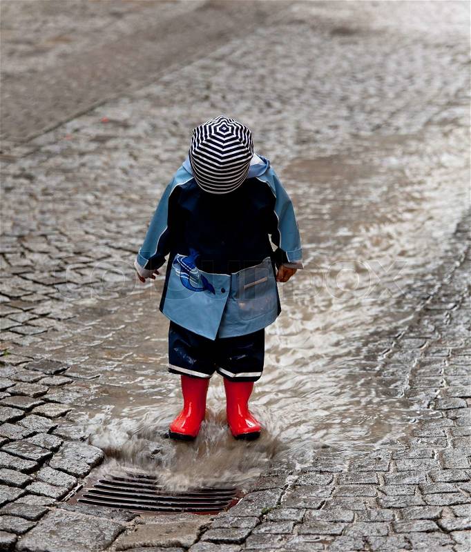 Child with rain gear and have fun playing in the rain, stock photo