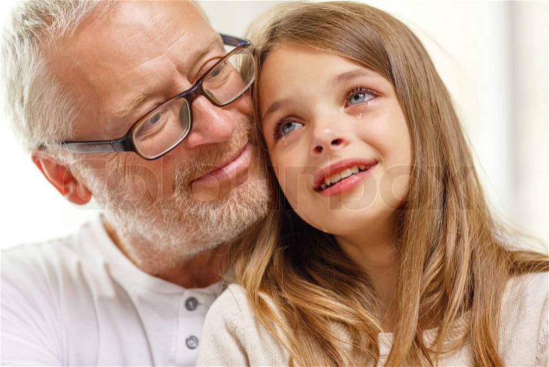 Family, support, childhood and people concept - grandfather with crying granddaughter at home, stock photo