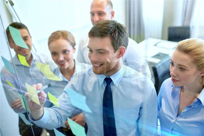 Business, people, teamwork and planning concept - smiling business team with marker and stickers working in office, stock photo