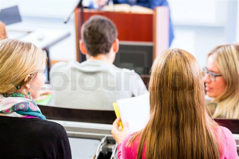 College professor giving lecture for students standing at desk, stock photo
