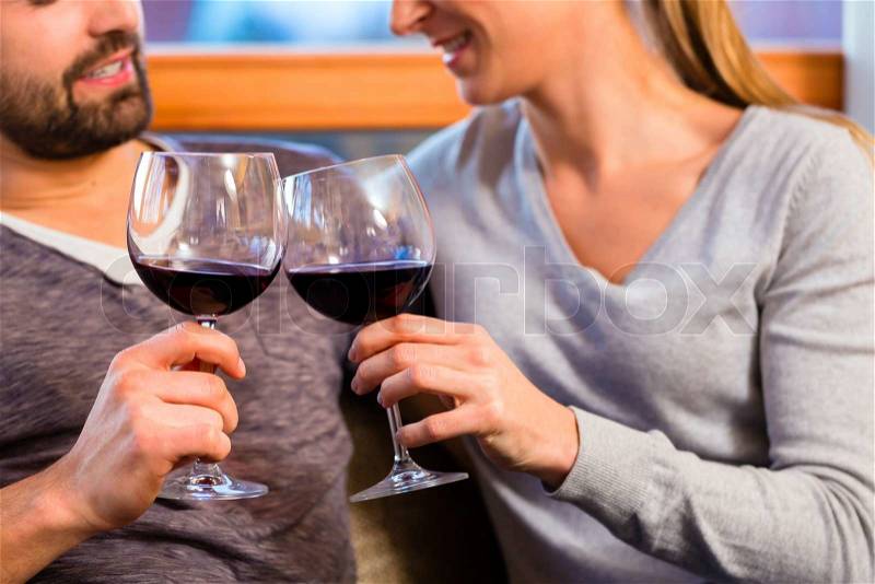 Young handsome couple drinking red wine at home, stock photo