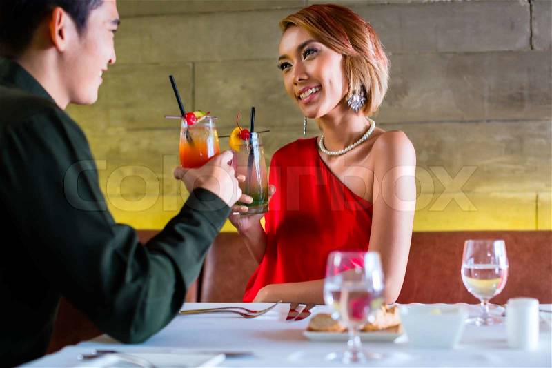 Asian couple drinking cocktails in fancy bar, stock photo