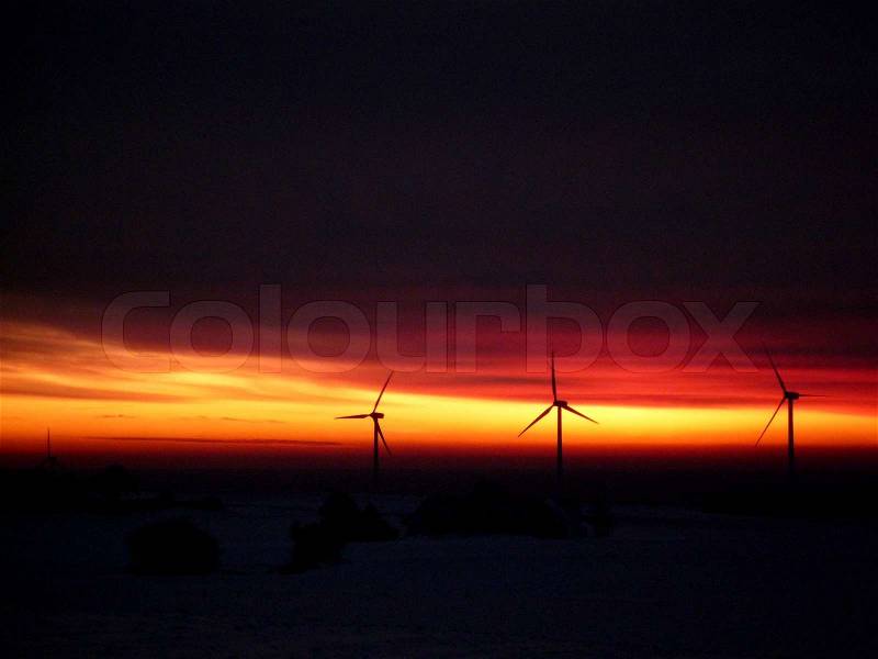 Windmills power the electrical grid in sunset, stock photo