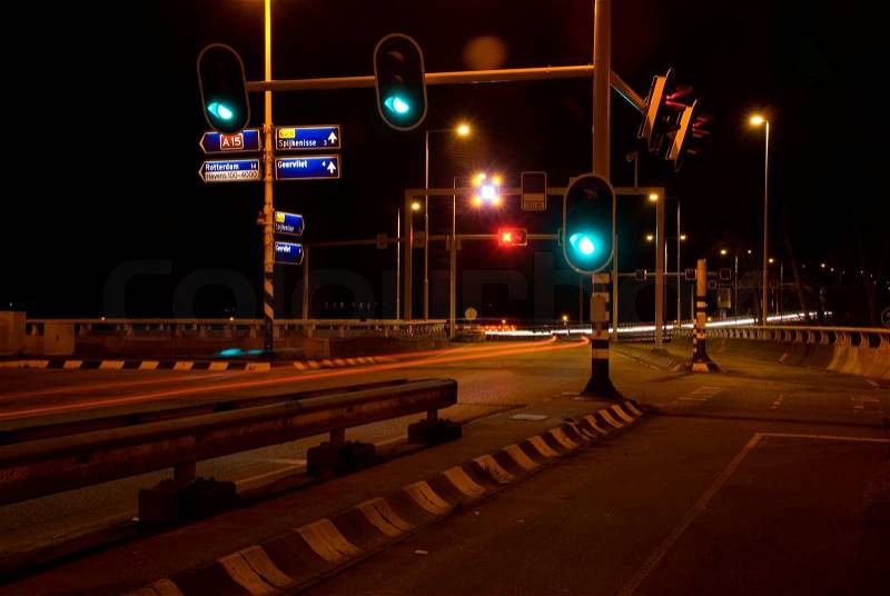 Evening street with cars speeding over the highway and the streetlight on green, stock photo