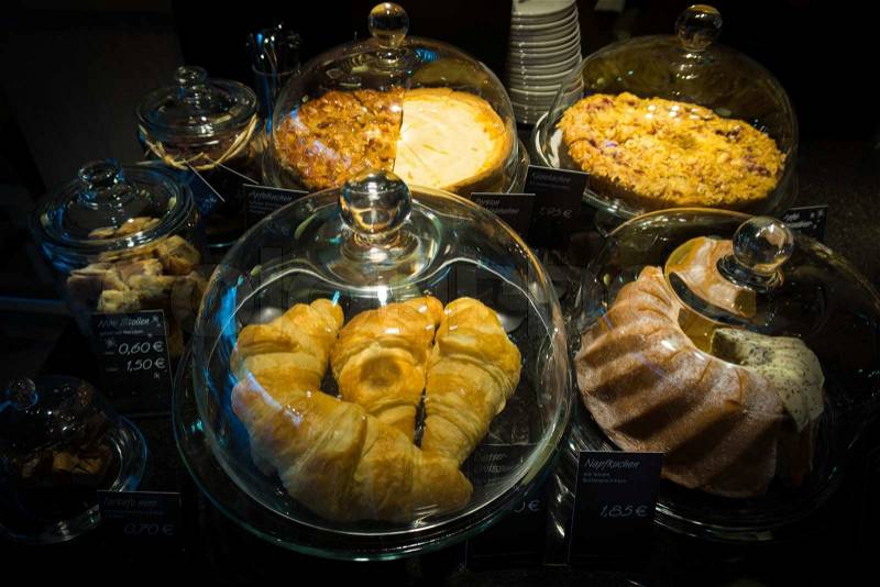 Cakes under bell-glass on display. bakery glass case full of different pieces of cakes, stock photo