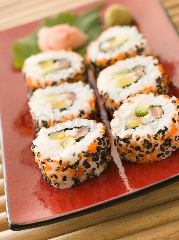 Plate of Inside-out Sushi Rolls decorated with roe and sesame seeds, stock photo