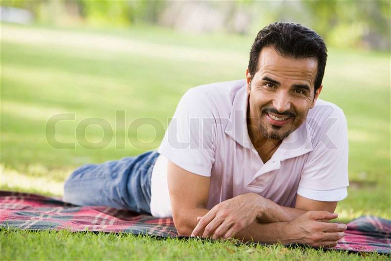 Man relaxing in park laying on blanket, stock photo