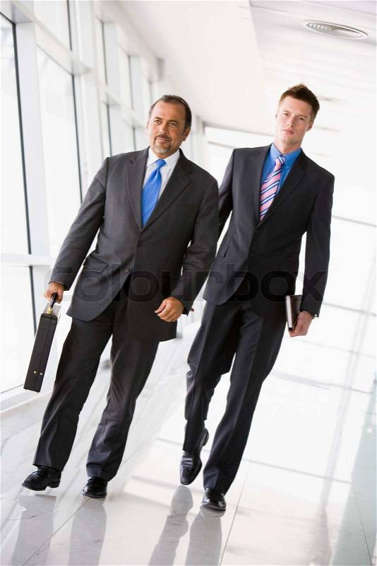 Two businessman walking through office lobby, stock photo