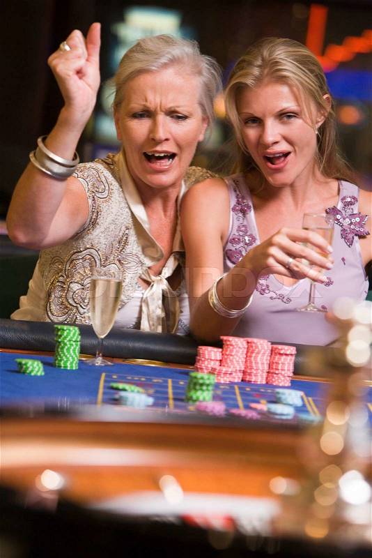 Two women gambling at roulette table in casino, stock photo