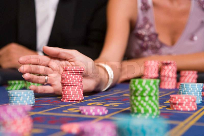 Close up of woman placing bet on roulette table in casino, stock photo