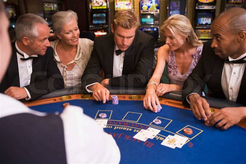 Five people sitting around blackjack table in casino, stock photo