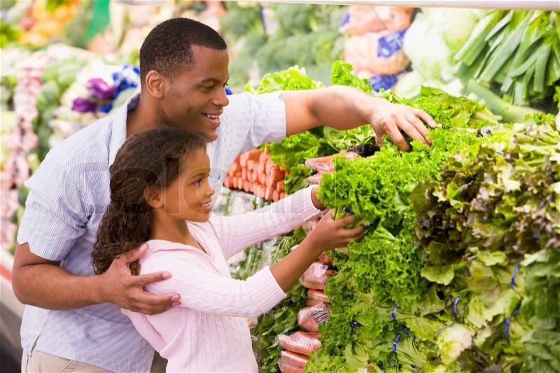 Father and daughter in supermarket produce section, stock photo