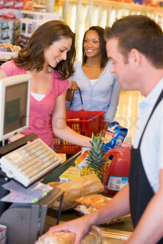 Woman paying for groceries at supermarket checkout, stock photo