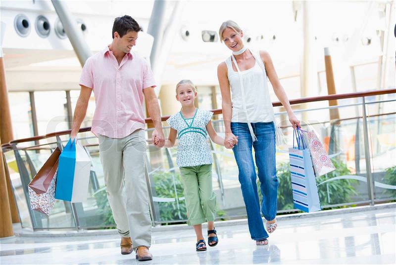 Family shopping in mall carrying bags, stock photo