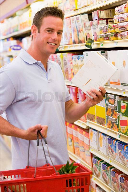 Young man grocery shopping in supermarket, stock photo