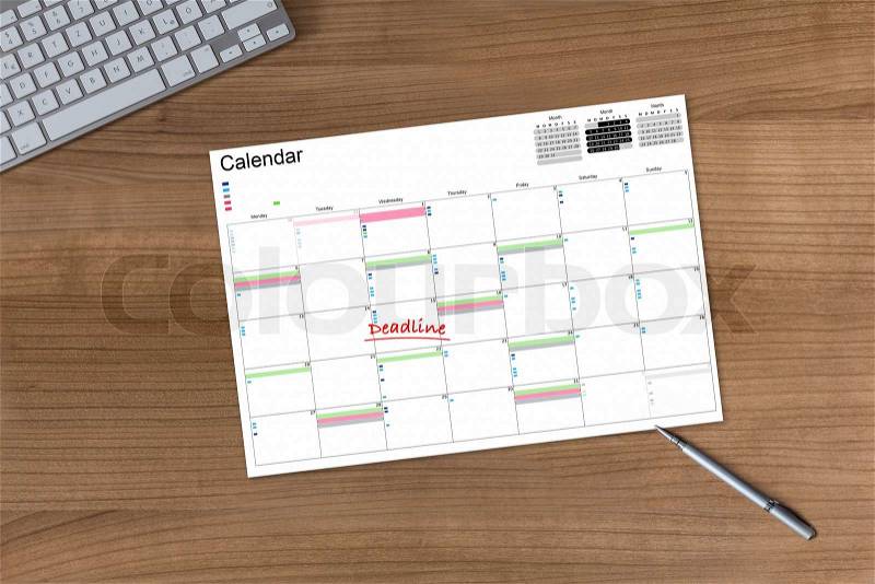 Calendar with the word Deadline on a wooden table with modern keyboard and silver pen, stock photo