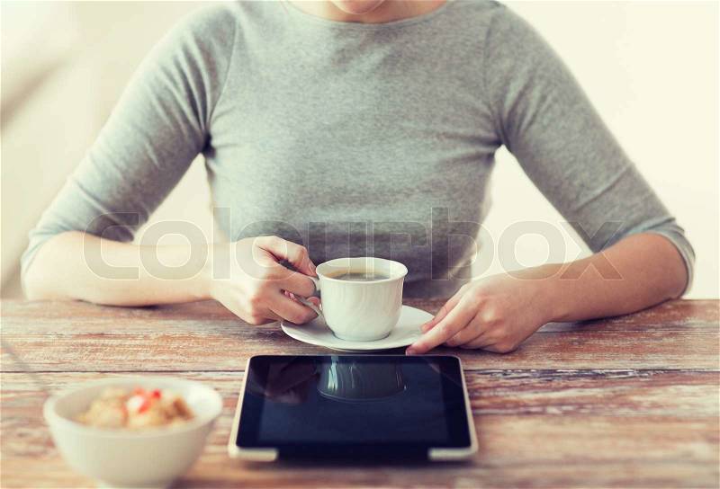 Health, technology, internet, food and home concept - close up of woman drinking coffee and using tablet pc computer, stock photo