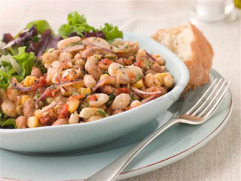 Bowl of Tuscan Bean Salad with Dressed Leaves and Crusty Bread, stock photo