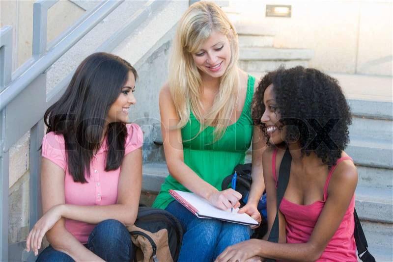 Group of three female students sitting on stairway, stock photo