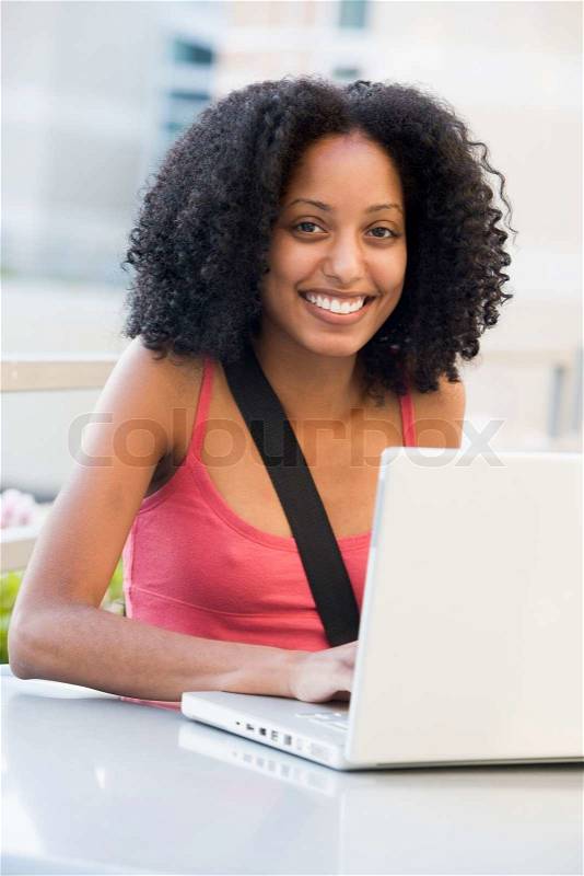 Female university student using laptop outside, stock photo