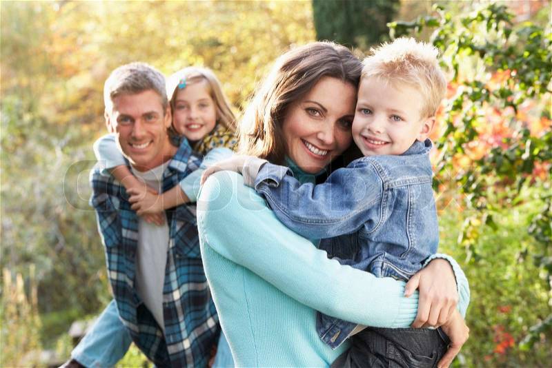 Family Group Outdoors In Autumn Landscape With Parents Giving Chiildren Piggyback, stock photo