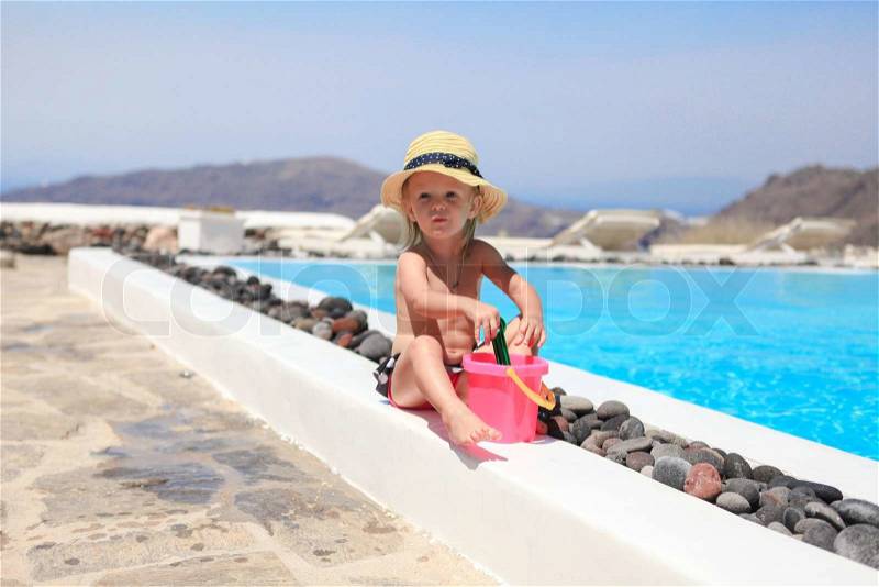 Adorable little girl near pool during greek vacation in Santorini, stock photo