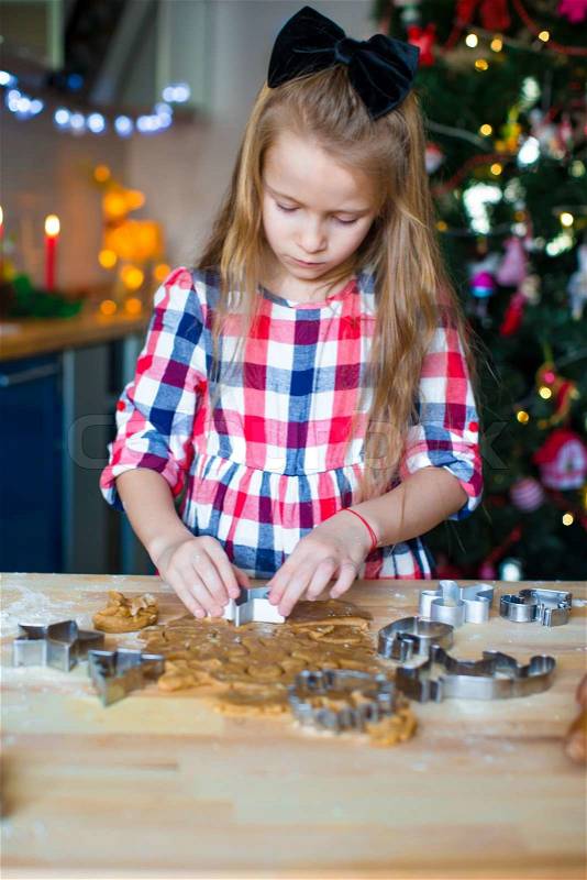 Little girl baking gingerbread cookies for Christmas at home kitchen, stock photo