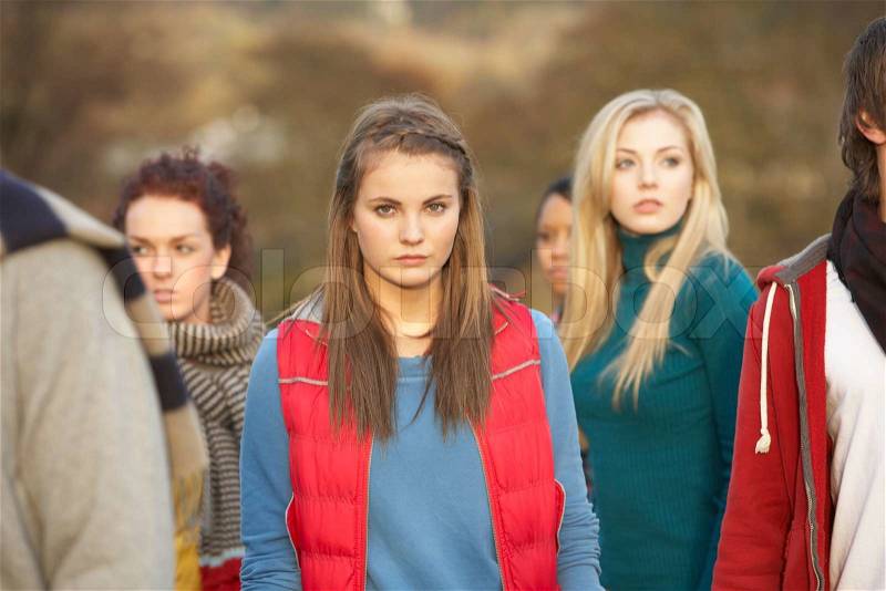 Teenage Girl Surrounded By Friends In Outdoor Autumn Landscape, stock photo