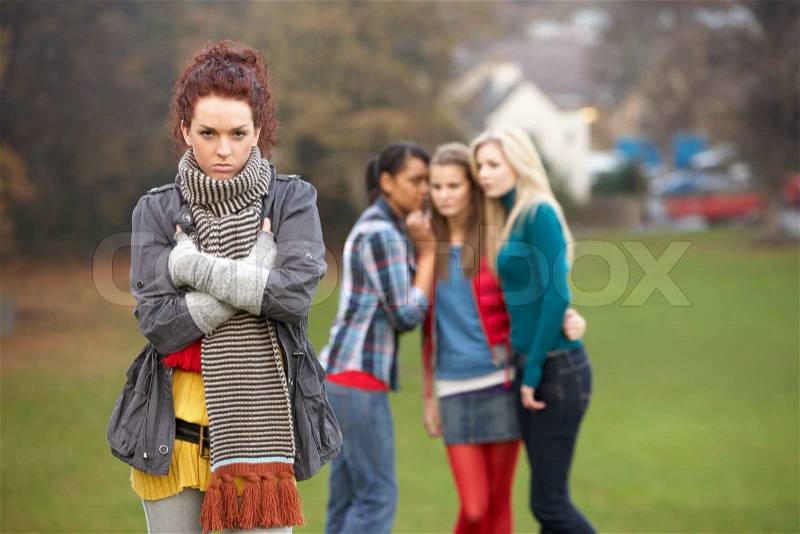 Upset Teenage Girl With Friends Gossiping In Background, stock photo