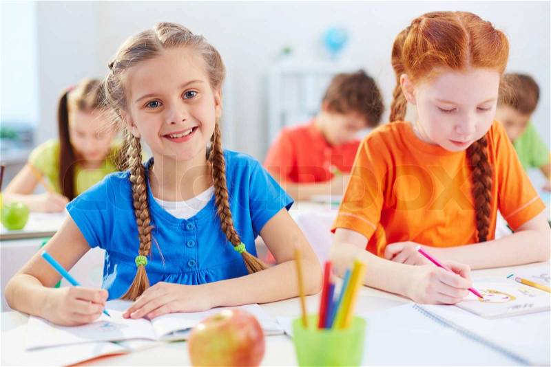 Pretty pupil drawing at lesson with her friend near by, stock photo