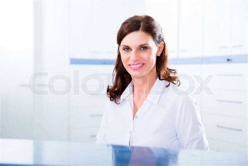 Doctors nurse with telephone in front desk making appointment with patient, stock photo