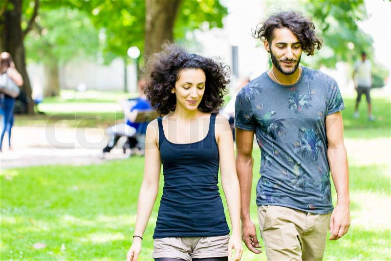 Couple, Latin man and woman, walking holding hands over meadow, stock photo