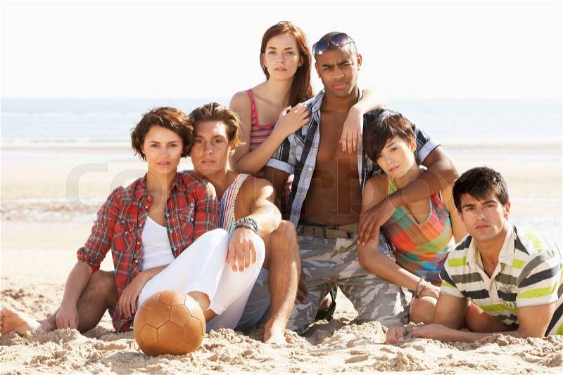 Group Of Friends Relaxing On Beach With Football Together, stock photo