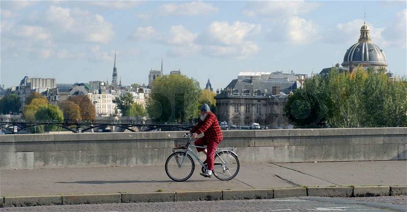 Old man on bicycle on bridge in Paris, France, stock photo