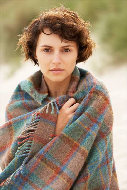 Young Woman Standing In Sand Dunes Wrapped In Blanket, stock photo