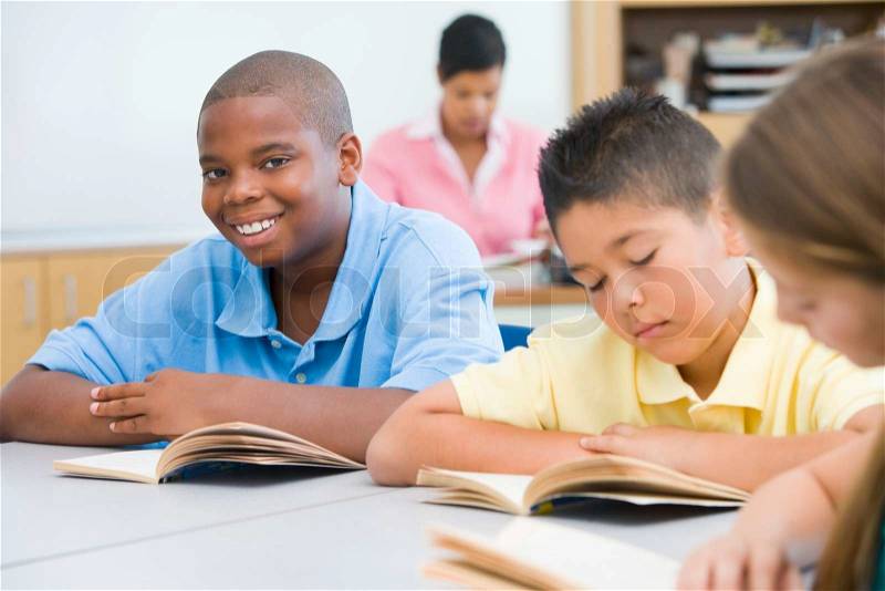 Group of pupils reading books at desk, stock photo