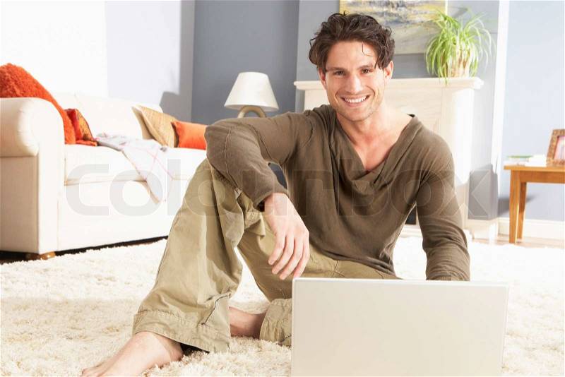 Man Using Laptop Relaxing Laying On Rug At Home, stock photo