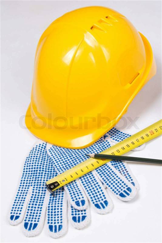 Builder\'s tools - yellow helmet, work gloves, pen and measure tape over white background, stock photo