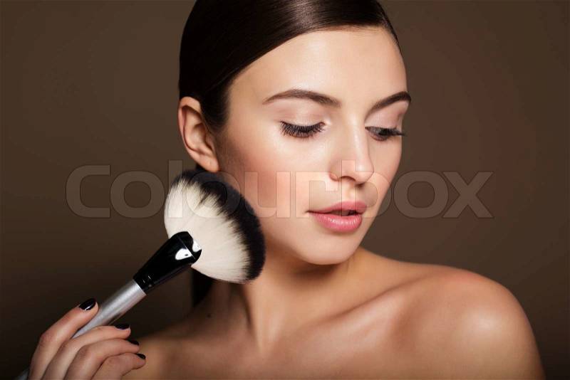 Portrait of a naturally beautiful woman is holding makeup brushthat makes skin flawless and perfect, stock photo